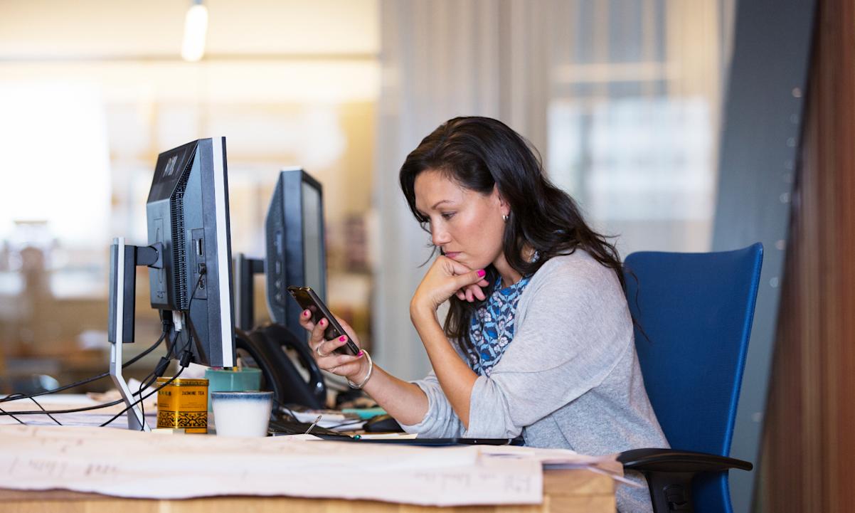 A woman looking at her phone in the office