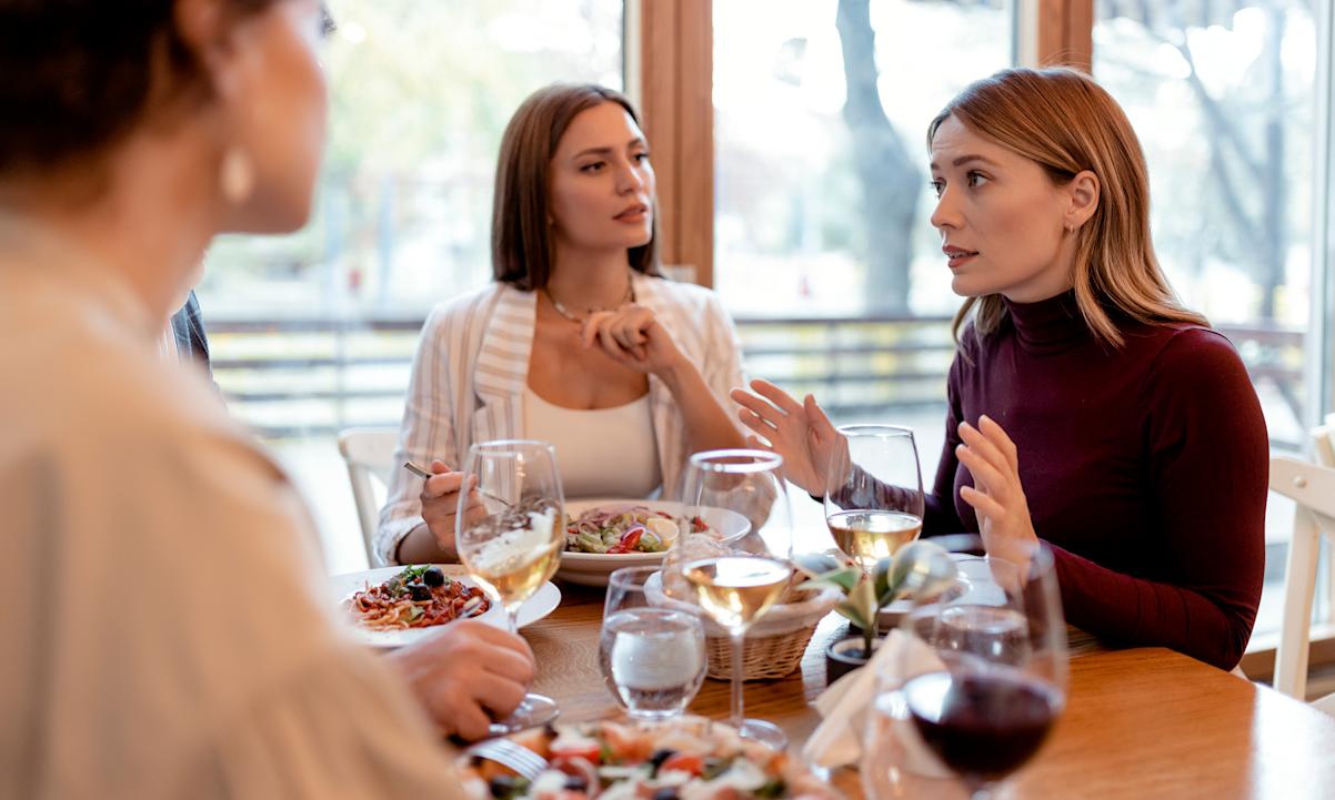 A group of women sitting at a table eating and talking