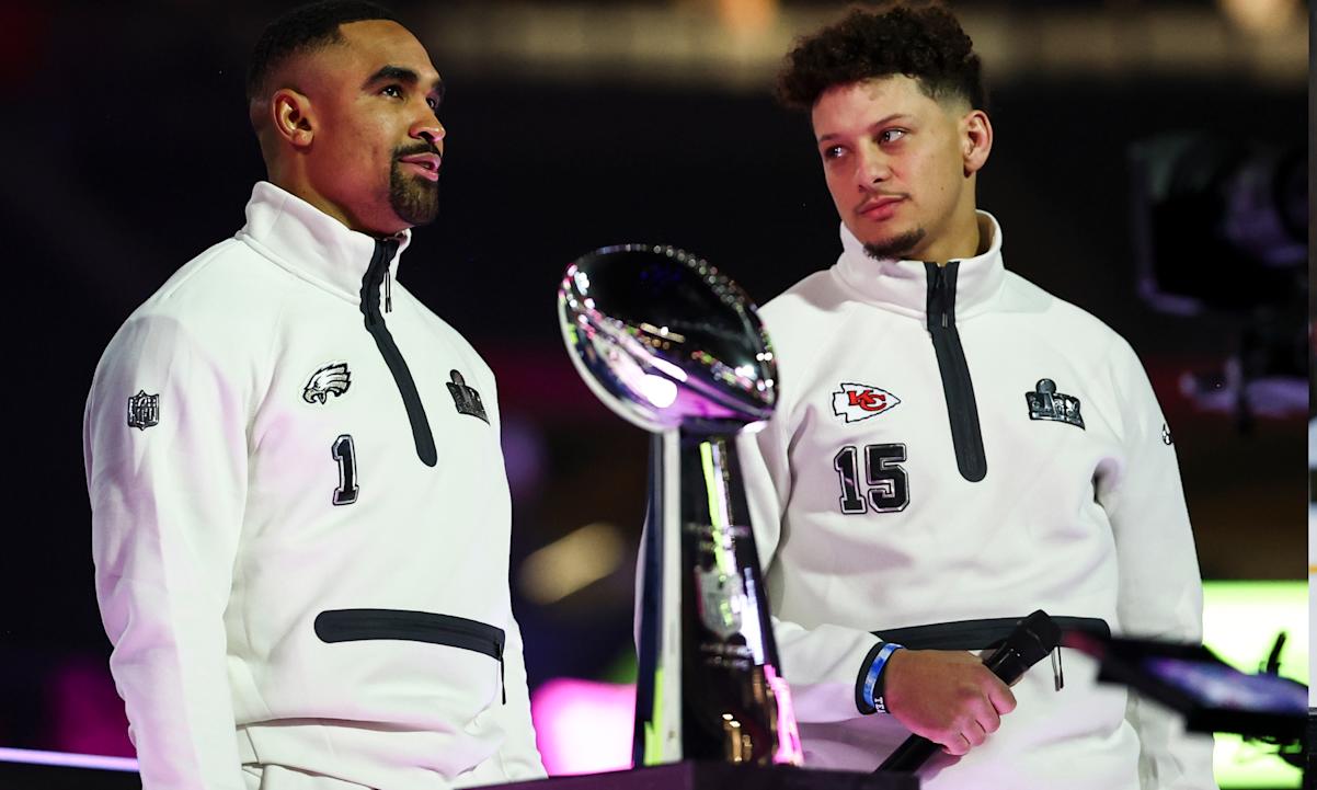 Jalen Hurts #1 of the Philadelphia Eagles and Patrick Mahomes #15 of the Kansas City Chiefs stand on stage next to the Vince Lombardi Trophy